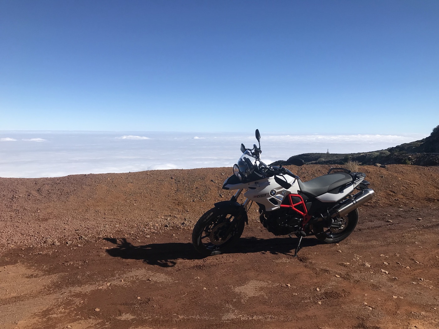 BMW-Motorrad auf rotem Vulkanboden am Roque de los Muchachos über dem Wolkenmeer
