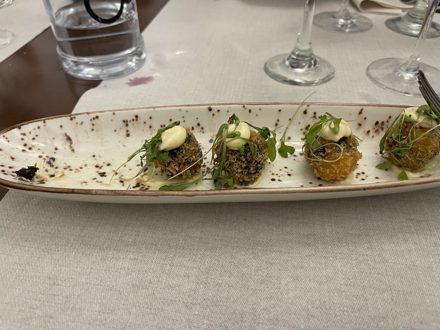 Frittierte Blutwurst-Bomben (Morcilla) mit Microgreens und Aioli auf länglichem Teller im Restaurante Carmen El Paso